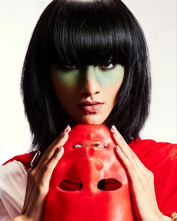 A close-up of a high-concept look featuring a sharp black bob wig and green color-blocking on the skin. This kind of work is about creating a memorable character, not just a makeup look.