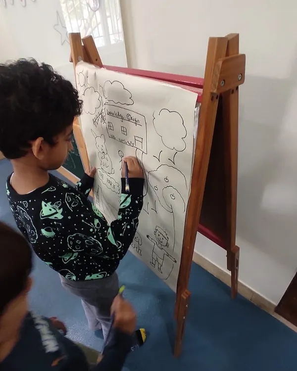 Our K1 and K2 students bring grammar to life by drawing and identifying nouns. This collaborative drawing on an easel shows how we make abstract concepts like 'person, place, or thing' tangible and fun.