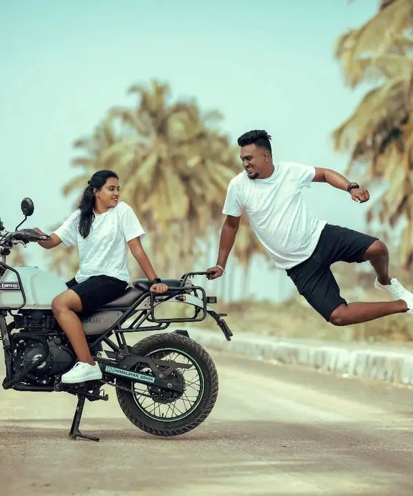 The ultimate shot for adventurous souls. A groom leaps joyfully in mid-air beside his bride on a Royal Enfield, capturing a moment of pure, uninhibited fun.