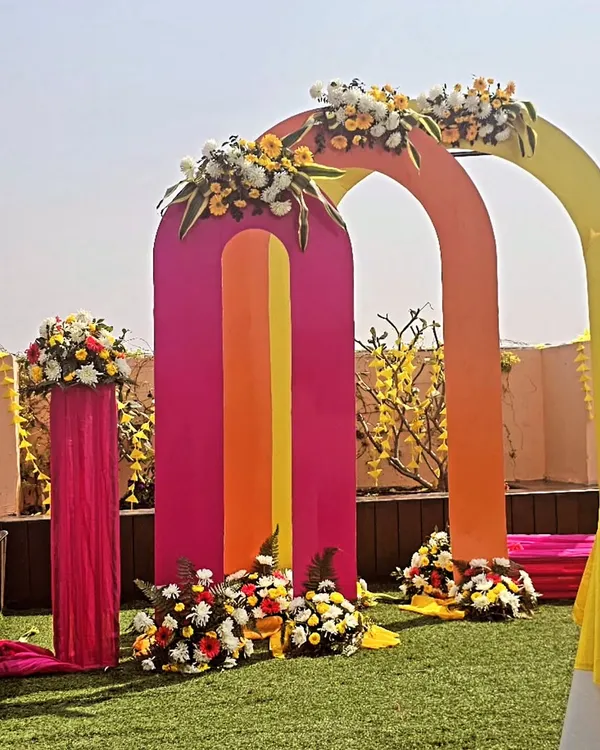 A modern take on haldi decor with a series of colorful arches. This setup is perfect for an outdoor lawn, adding a playful and artistic touch to your daytime ceremony.