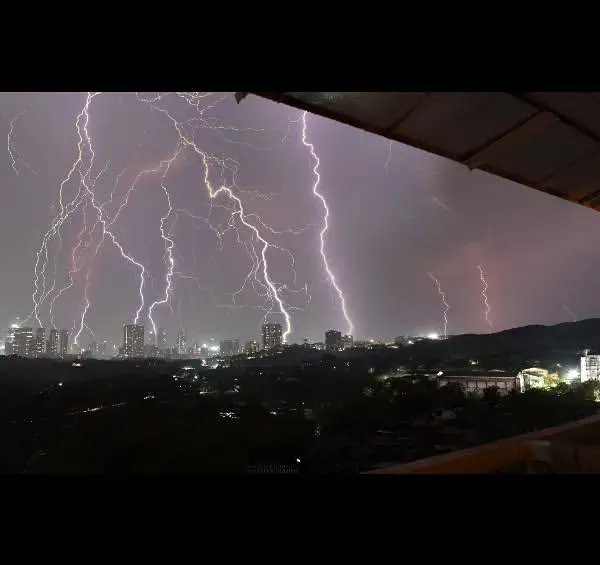 A panoramic view of the lightning storm over the Mumbai skyline, taken from our balcony. This wide shot shows the immense scale of the storm as multiple bolts strike across the city and hills.