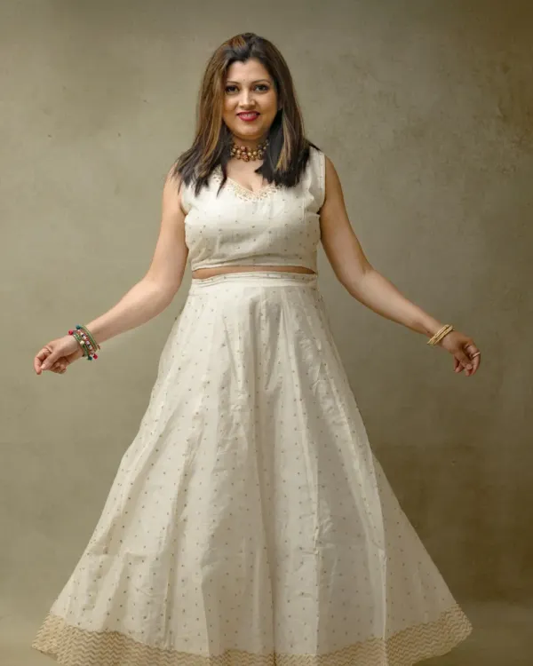 A joyful and elegant portrait. Her beautiful white ethnic dress and open, welcoming posture create a feeling of warmth and grace against a simple, textured studio background.