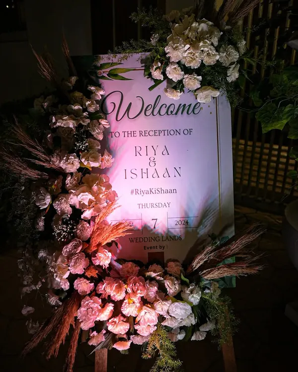 An elegant welcome to Riya and Ishaan's reception. The signage was framed with a lush arrangement of white roses and dried pampas grass, creating a sophisticated and romantic first impression for the evening event.