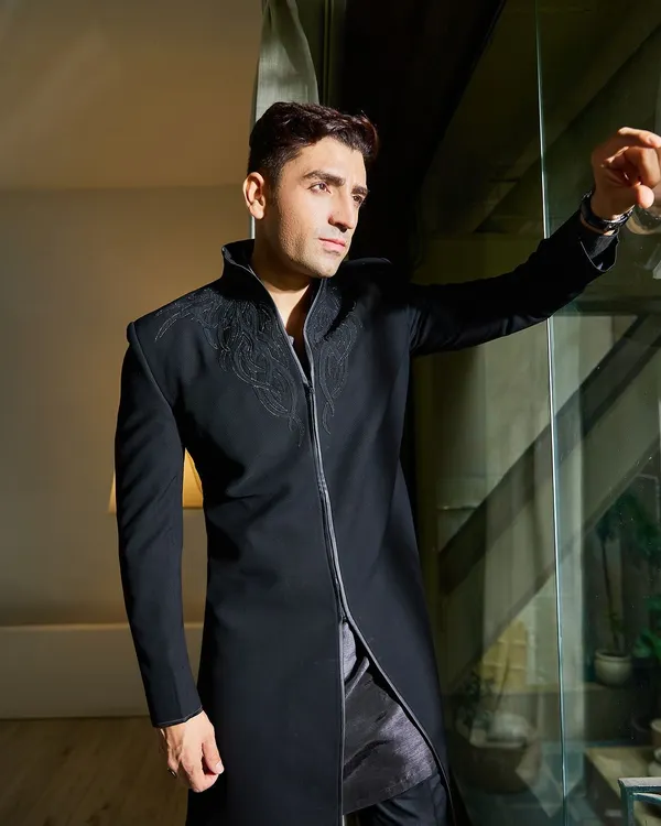 This black Indo-Western piece is all about modern drama. The longline jacket features intricate, tonal hand-embroidery around the high collar and a bold zipper front, creating a sharp, contemporary silhouette.