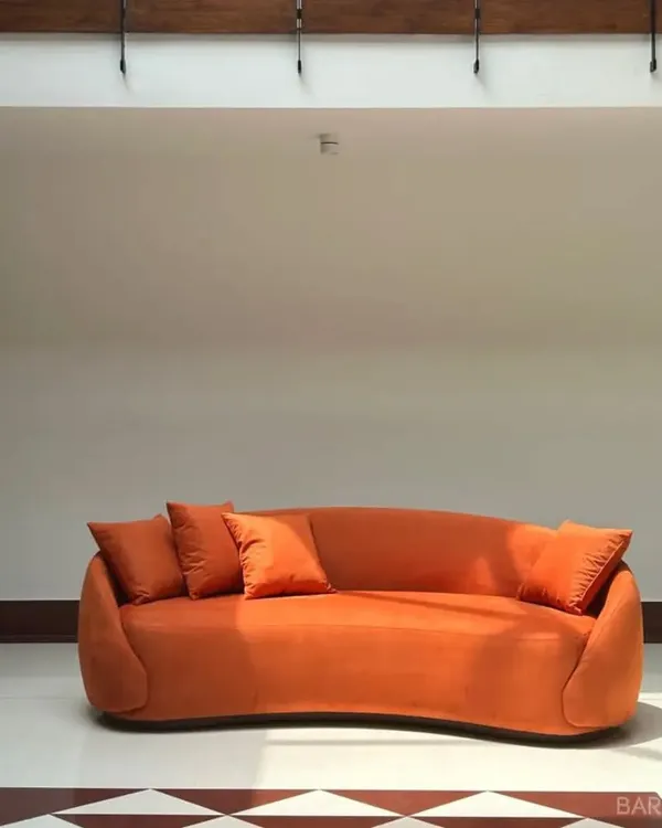 A close-up of the bold, curved orange sofa. This piece shows how a single item of furniture can define the character of a room.