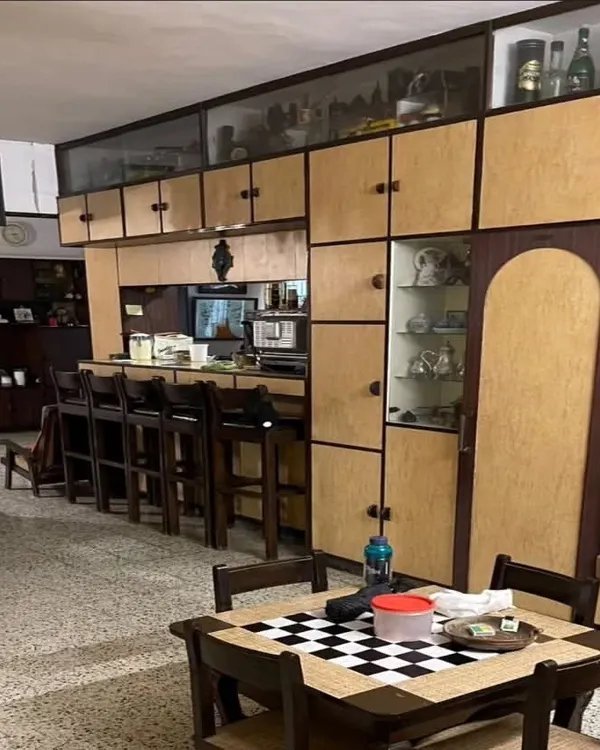 **BEFORE:** A living area from the 1980s, filled with heavy, dark wood cabinetry, a built-in bar, and terrazzo flooring, which made the space feel dated and compartmentalized.