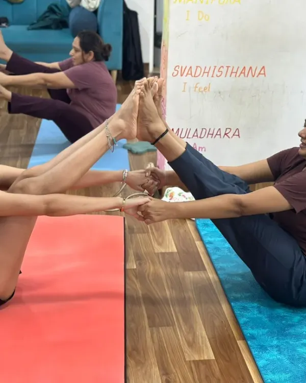 Move, flow, and grow together. Two members of our tribe connect in a partner boat pose, supporting each other to find balance and strength.
