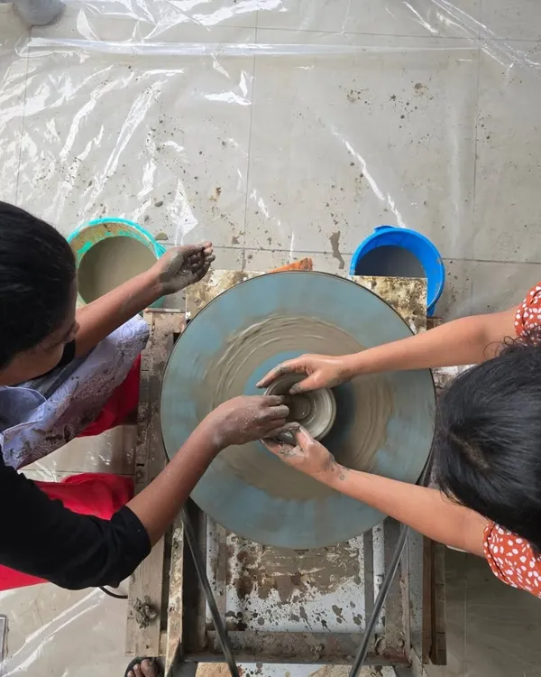 This is where it all starts. A top-down view of two people working together on the pottery wheel, learning to center the clay. It's a true team effort.