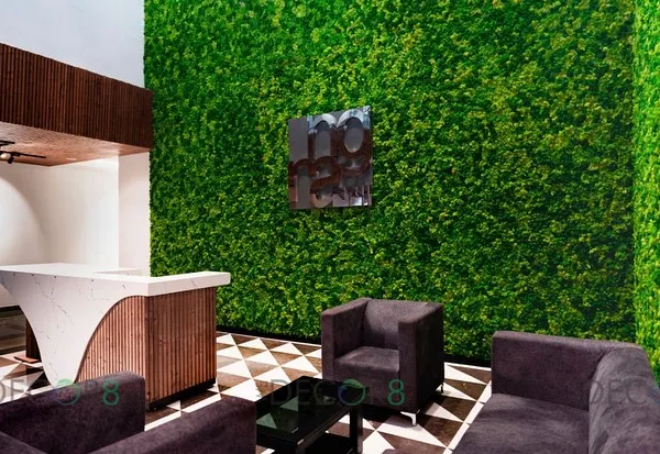 A full-view of a reception area transformed by a floor-to-ceiling preserved moss wall. This installation immediately establishes a biophilic and high-end atmosphere for visitors, complemented by the geometric flooring and modern furniture.