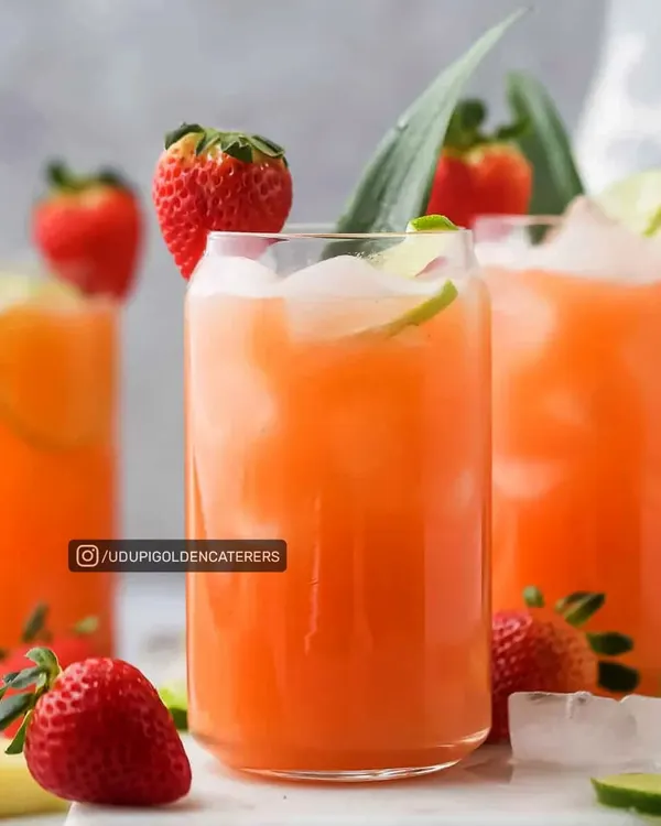A refreshing Strawberry Pineapple Punch served over ice with a lime garnish. This is one of our many colorful and delicious welcome drinks perfect for summer events.