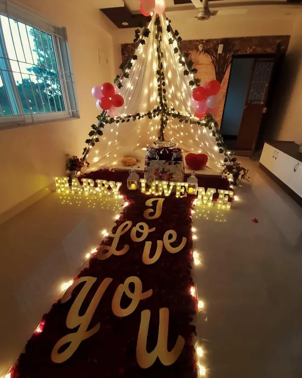 This is my signature romantic canopy setup, perfect for a proposal or anniversary. It features a "red carpet" of rose petals leading to a beautifully lit tent, with "I Love You" signs and marquee letters that say "Marry Me".