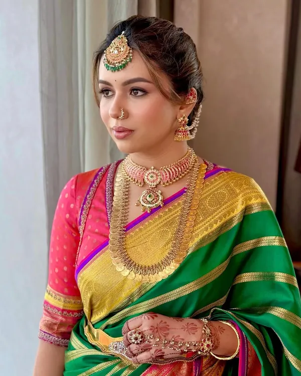 A portrait of modern South Indian elegance. The makeup is focused on creating a flawless base, with defined eyes and a warm lip color that complements the vibrant hues of her Gaurang saree.
