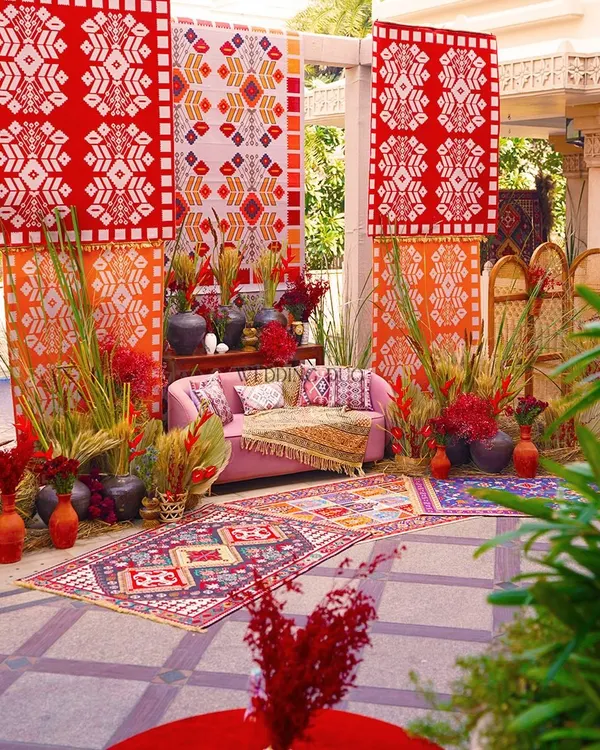 Elevating a Bhaat ceremony with a vibrant mix of patterns and textures. We used bold red and orange printed backdrops, colorful rugs, and fuchsia florals to create a joyful and festive atmosphere.