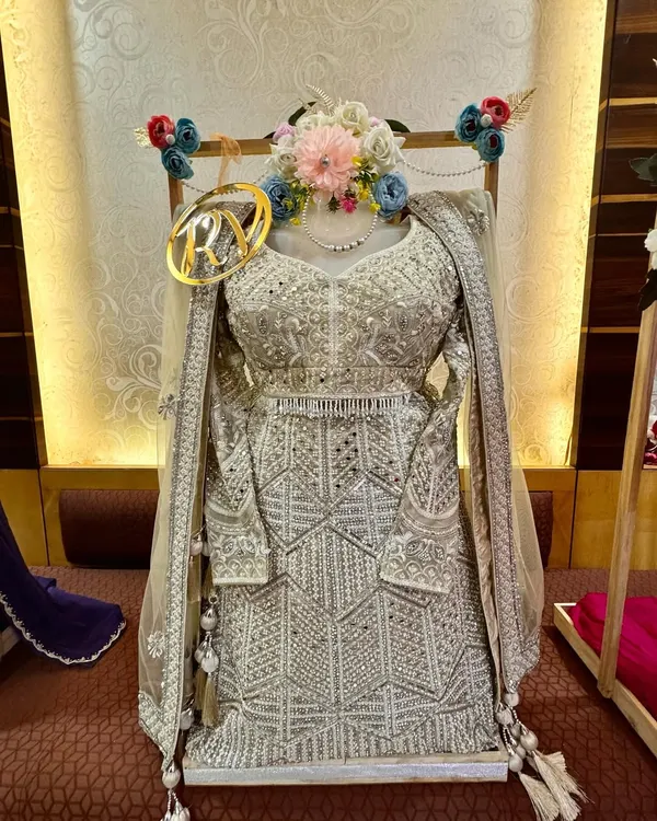 A close-up of this stunning silver lehenga, packed and ready for a bride's trousseau. I used a mannequin form to display its intricate work and added a floral garland and a custom initial tag for a complete look.