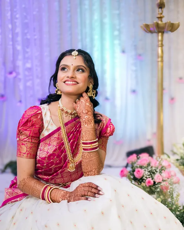 A beautiful South Indian bride, looking up with a dreamy smile. The soft lighting and floral background create a truly angelic portrait.