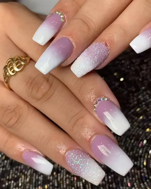 A stunning ombre effect fading from a soft lavender to white, with accent nails covered in sugar glitter and rhinestones at the cuticle.