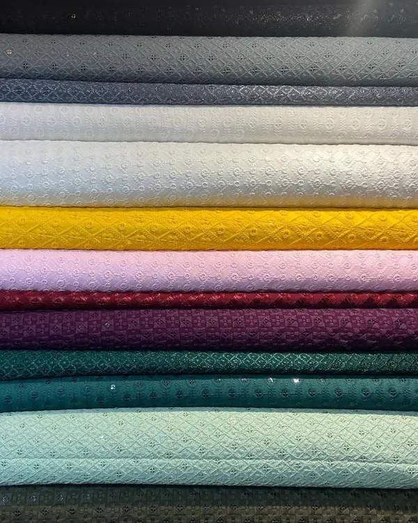 A stack of pure Chikankari fabrics, showcasing the range of colors I offer for bespoke kurtas. This traditional hand-embroidered textile from Lucknow is a popular choice for its elegance and breathability.