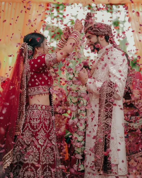 This is the moment. The world fades away and all that's left is the joy of starting a new life together, showered in blessings and petals. Capturing the peak of the Varmala ceremony is about freezing that pure, unscripted happiness.