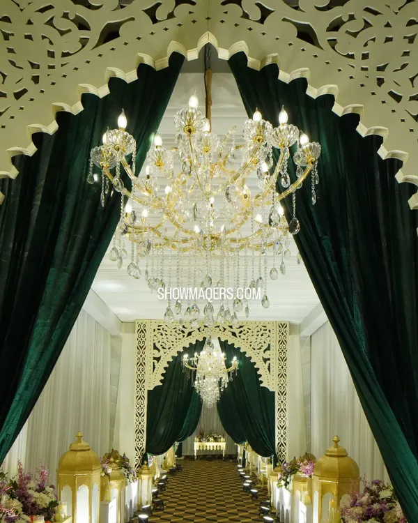 A majestic entrance for a Sufi-themed reception, featuring grand white arches with intricate jali work and rich, dark green velvet curtains.