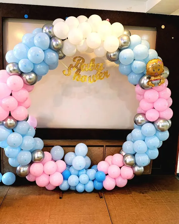 A classic baby shower decoration with a pink and blue balloon ring. This setup is perfect for gender reveal parties and includes themed props like "BABY" blocks.