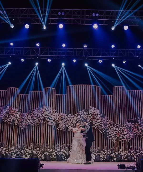 A wide shot of a spectacular Sangeet stage with dramatic lighting and floral decor. We capture the grandeur of your event design.