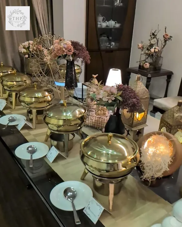 An elegant buffet setup for an intimate party of 15-20 guests. We use beautiful brass chafing dishes, floral arrangements, and ambient lighting to create a warm and inviting atmosphere in your home.