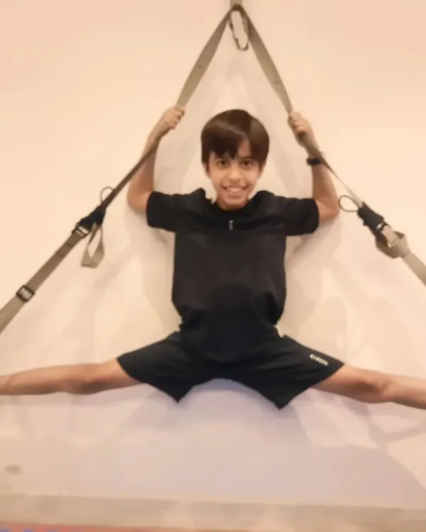 We use suspension straps to assist with drills like this wall split. This method allows the student to control the intensity of the stretch, building both flexibility and confidence safely.