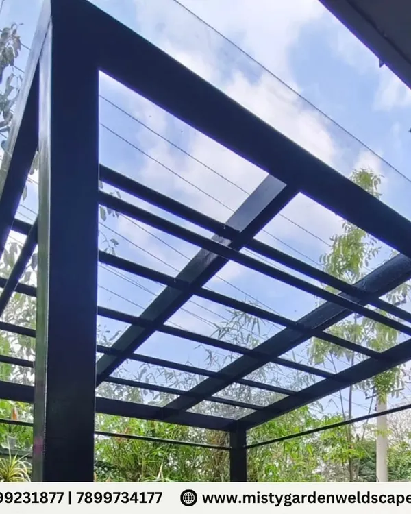 This completed pergola in Chikkagubbi features a 3mm compact sheet roof on a sturdy black metal frame. It provides shade and rain protection while maintaining a modern, open feel.