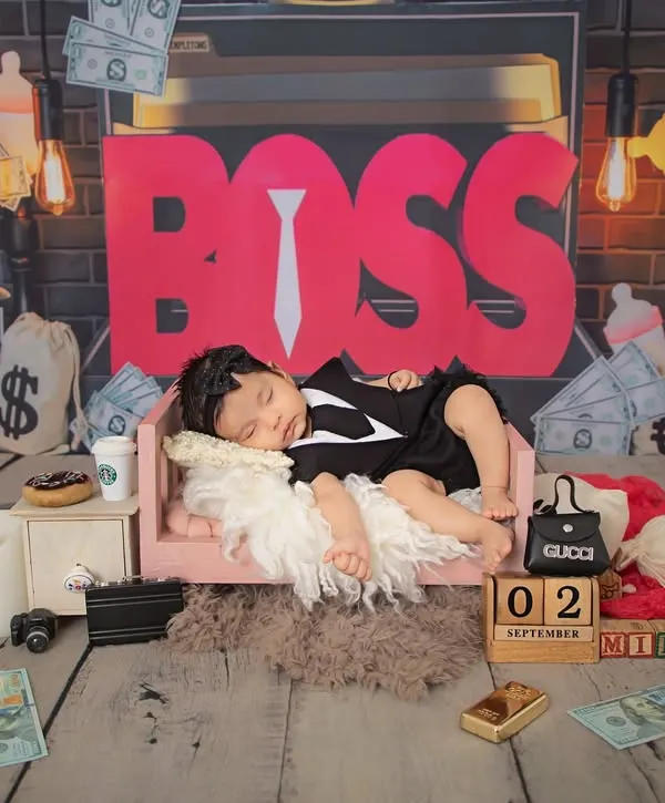 Here is the little boss, taking a well-deserved nap. This wide shot shows the full "Boss Baby" setup, complete with money bags and a tiny briefcase, for a truly unique newborn photo.