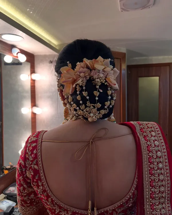 A close-up of a royal bridal transformation, focusing on the intricate floral bun. We used a combination of fresh flowers and delicate pearl accessories to create this elegant and timeless hairstyle.