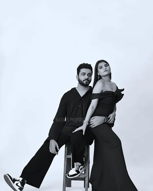 A stylish black and white studio portrait of a couple. The composition and posing create a modern, high-fashion look.