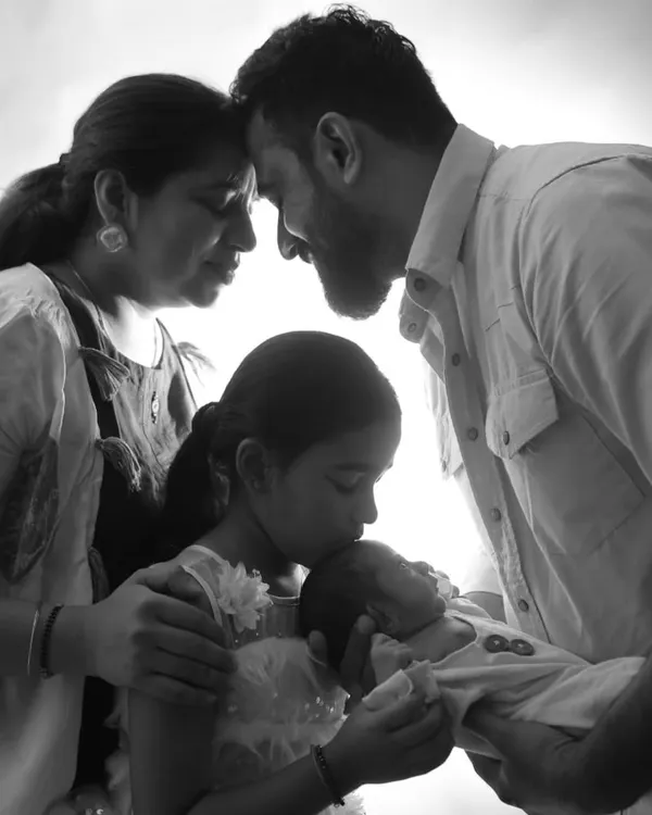 A timeless black and white portrait capturing the complete love of a family welcoming their newborn. I focus on these tender connections, with the older sister gently kissing her new sibling.