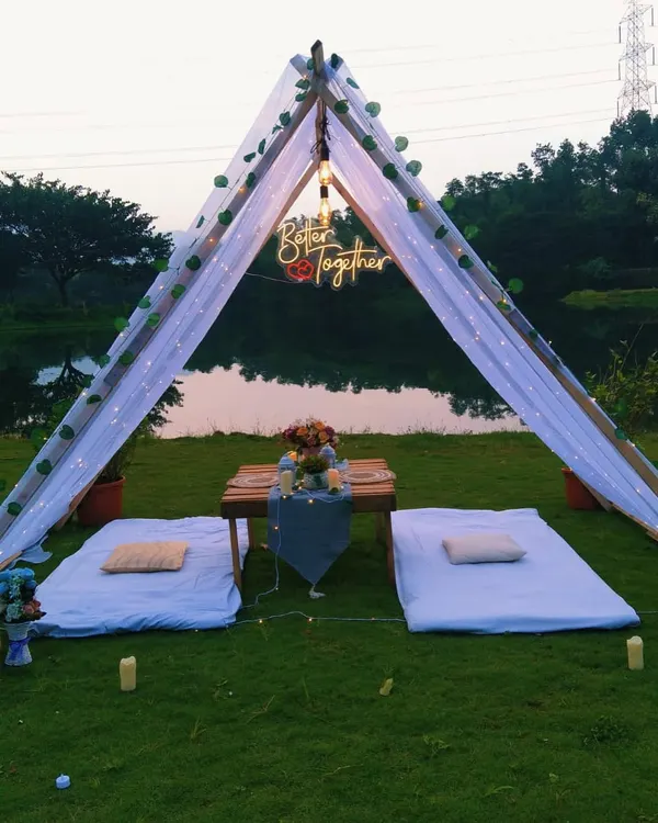 A perfect romantic escape. I created this intimate picnic setup with a lakeside view, complete with a canopy tent, comfortable seating, and a beautifully set table for two.