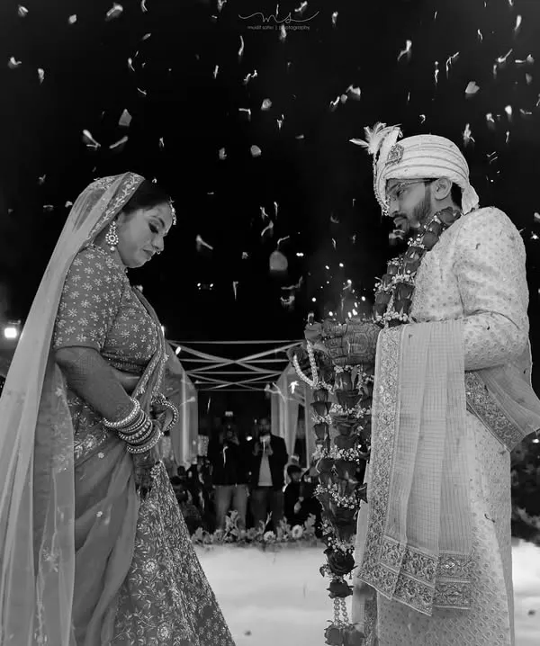 A powerful black and white shot of the Varmala exchange. The dramatic lighting and surrounding fireworks create a timeless and unforgettable image of this pivotal wedding moment.