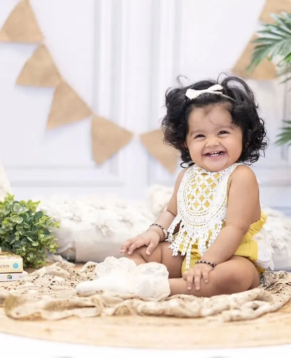 That smile says it all. This happy little girl is celebrating her first birthday with a fun, boho-themed studio session.