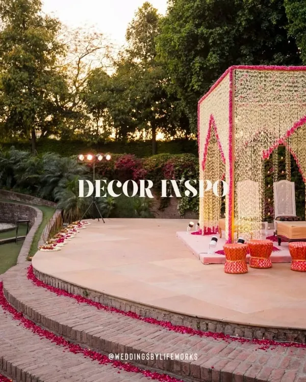 A stunning mandap decorated with strings of white and pink flowers, set in the beautiful outdoor amphitheater of Zorba, Delhi. This is decor inspiration at its finest.