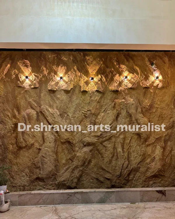 The finished stone mural for the fountain wall, complete with custom light fixtures. Before the water is turned on, you can see how the lighting highlights the deep, rugged texture we created by hand.