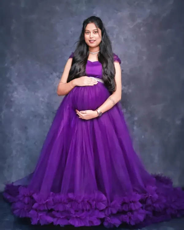 A full-length portrait in a royal purple tulle gown against a simple grey studio backdrop. This allows the vibrant color and design of the dress to be the main focus.
