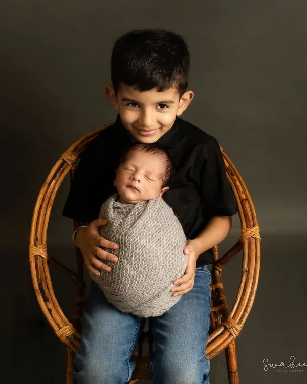 A proud big brother holds his newborn sibling. Capturing the start of this lifelong bond is one of the most special parts of my job.