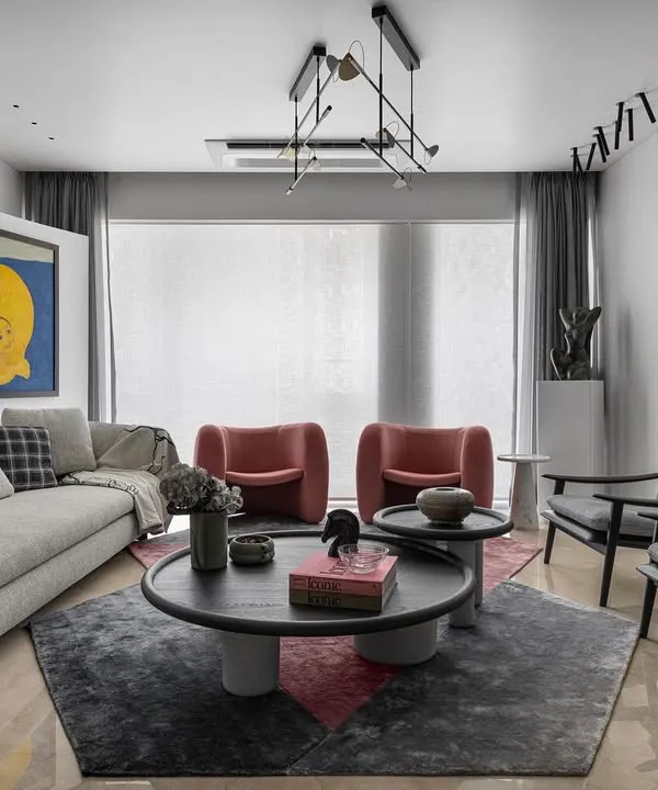 A luxuriously layered living room where art is the hero. The neutral sofa and geometric rug provide a sophisticated base for the bold yellow artwork and sculptural pink chairs, creating a space that is vibrant and full of personality.