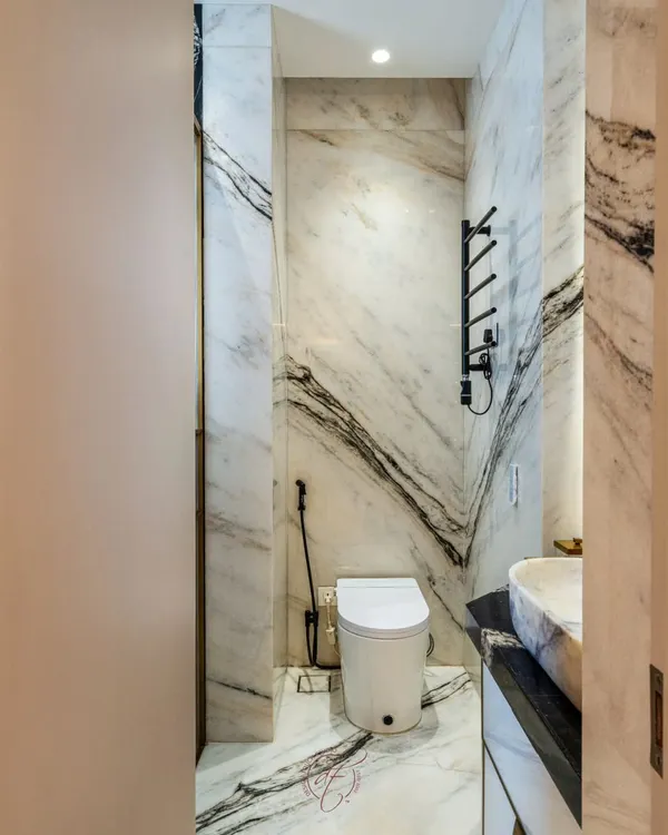 A glimpse into a bathroom ensuite defined by dramatic black and white book-matched marble. The design features a smart toilet and a heated towel rack, combining opulence with modern comfort.