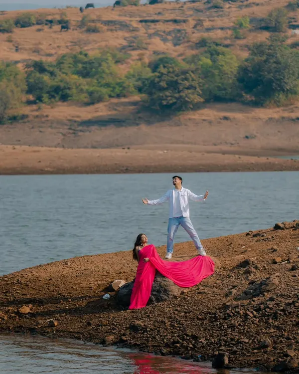 The ultimate Bollywood pose. With his arms outstretched and her vibrant pink saree flowing, this shot is a direct homage to the grand, romantic scenes of Indian cinema.