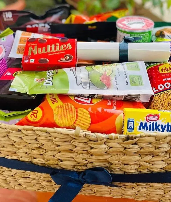 A classic snack lover's dream. This wicker basket is overflowing with a wide assortment of popular Indian snacks and chocolates, including Lays, Haldiram's Loo Bhujia, Nutties, and Milkybar. It's the perfect treat for any casual occasion.