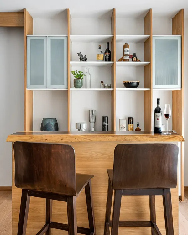 For the 'Pepper and Coffee' project, we designed this custom bar and shelving unit with a live-edge wood counter, creating a perfect spot for entertaining.
