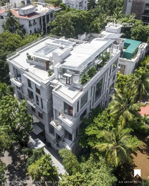 An aerial view of the Boat Club Apartments in Chennai, showing how the building's form is broken down into smaller volumes to reduce its mass and integrate with the surrounding green landscape.