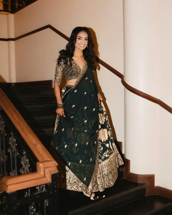 A glowing and gorgeous bride making her entrance. For her reception, we chose a stunning dark green and gold lehenga, paired with soft waves and a luminous makeup look.