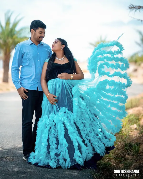 A beautiful shot of an expecting couple, where the dramatic, ruffled trail of the maternity gown creates a stunning visual against the open road. This shows how we style fashionable and memorable portraits.