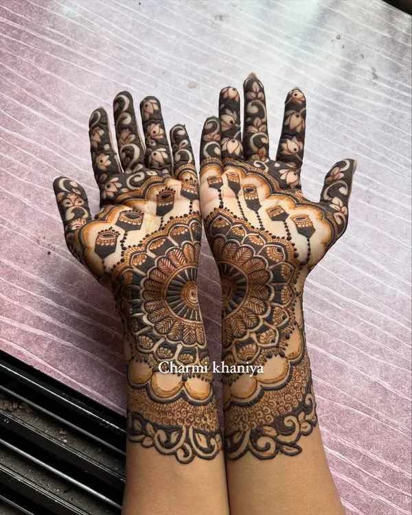 A beautiful henna design featuring a large, intricate mandala. The hanging 'jhumka' or earring motifs add a festive and celebratory touch, perfect for Karwa Chauth or Eid.