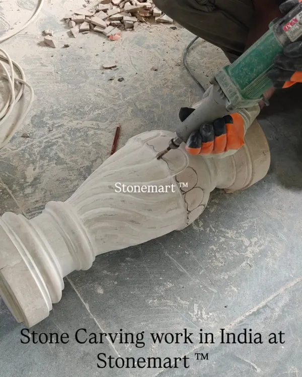 The process begins. An artisan uses a power tool to do the initial shaping of a stone pillar for a birdbath fountain. This is where the raw stone starts to take form.