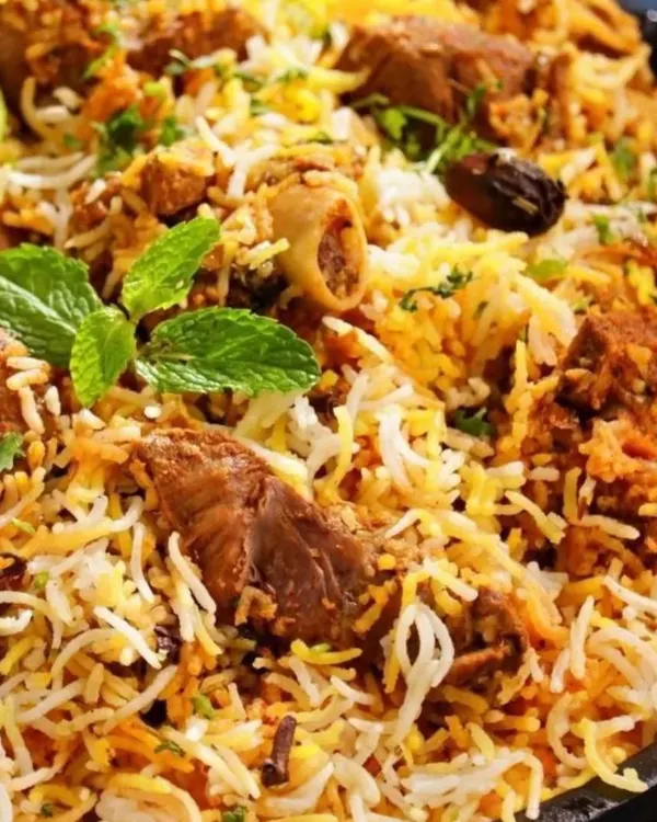 A close-up of my Chicken Biryani, showing the fluffy, distinct grains of rice and tender pieces of chicken. It's garnished with fresh mint and a squeeze of lime for that extra zest.